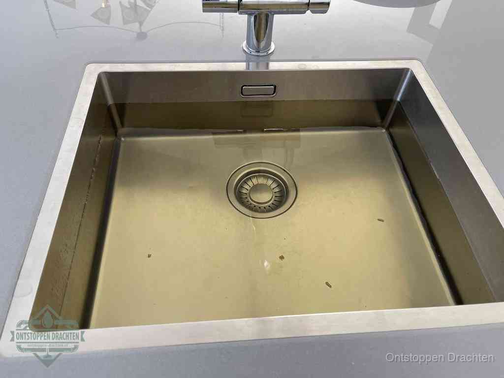 Stilstaand water in een rvs spoelbak dat niet wegloopt, een duidelijk signaal van een gootsteenverstopping in Drachten