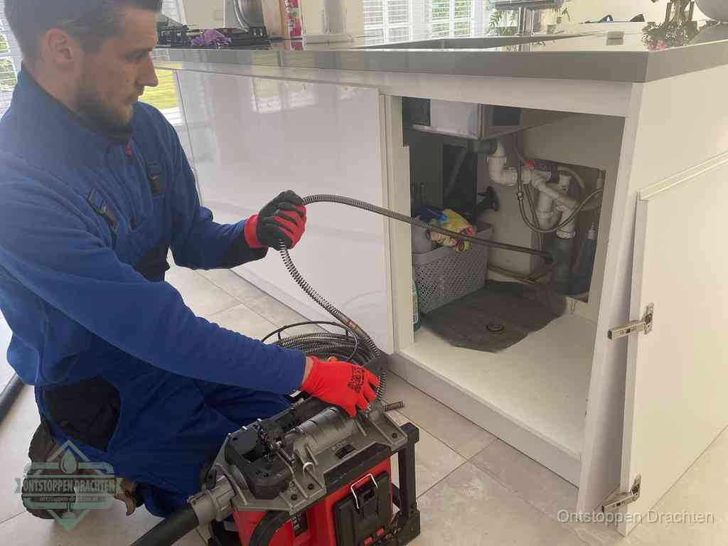 Een monteur reinigt de keukenafvoer grondig met een veermachine om terugkerende gootsteenverstoppingen te voorkomen in Drachten