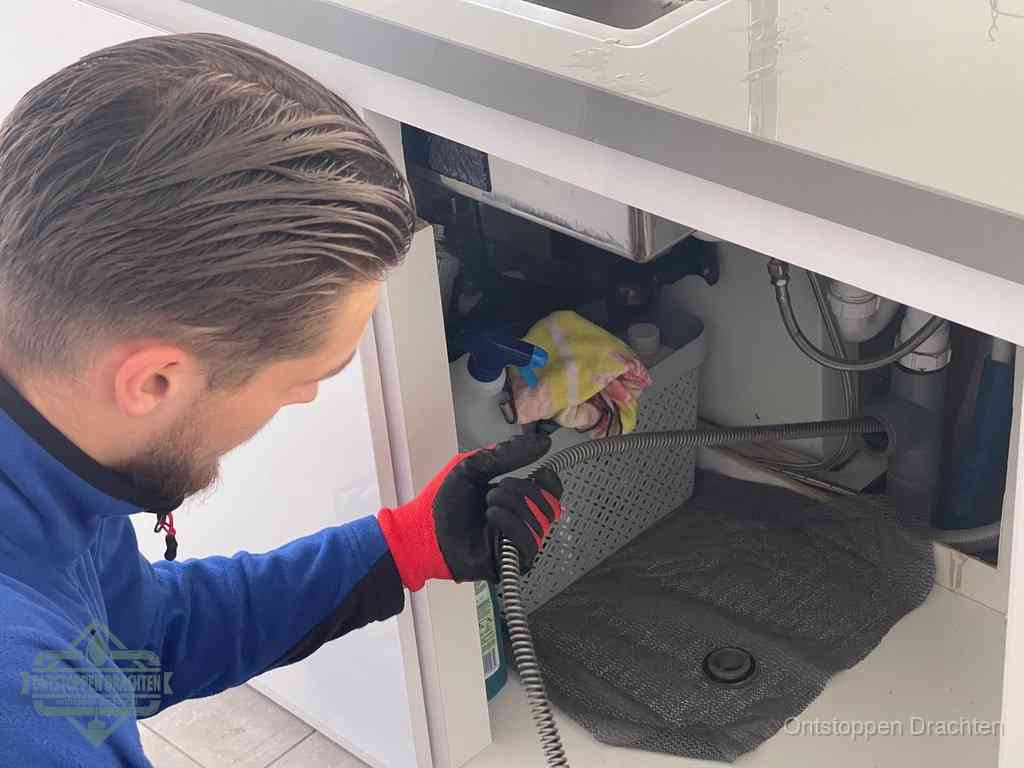 Een monteur voert een flexibele ontstoppingsveer in de afvoer om een verstopping voorbij de bocht van het toilet te bereiken in Drachten