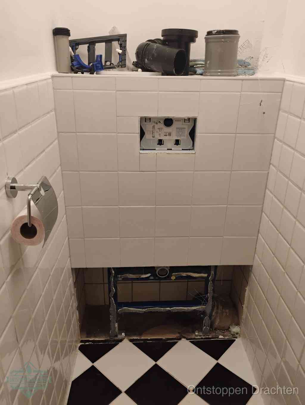Een toiletruimte waar het hangtoilet en de inbouwreservoir-onderdelen zijn vrijgelegd voor onderhoud, periodiek nazicht voorkomt een wc-verstopping in Drachten